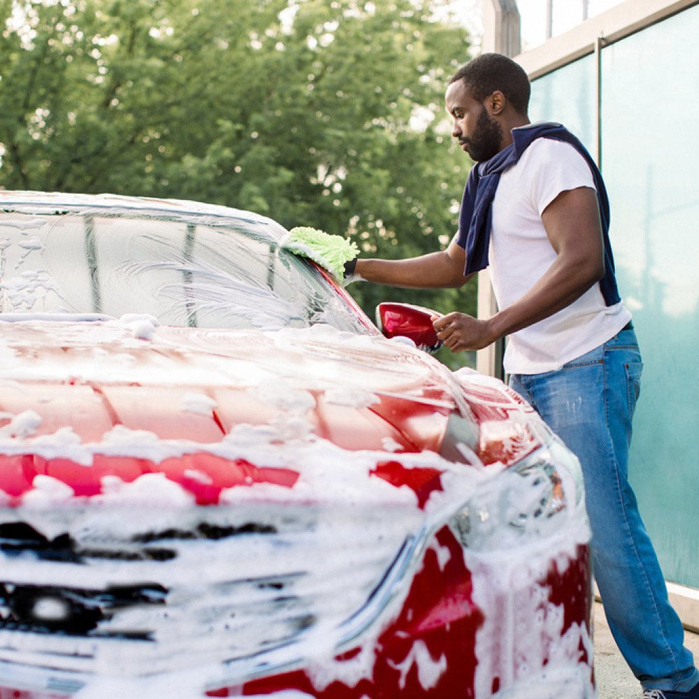 Hand wearing green chenille car wash mitt soaping up vehicle